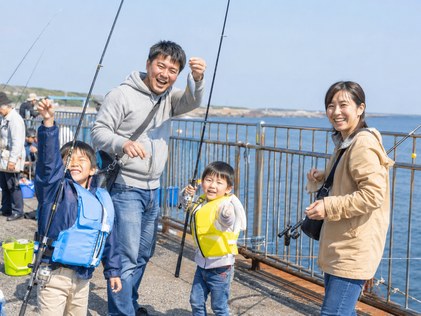 堤防で家族と釣りをする様子