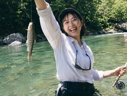 渓流で魚を掲げる人