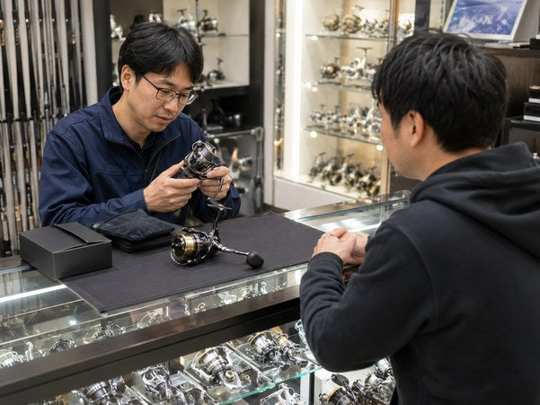 店頭でリールを手に取る客とスタッフ